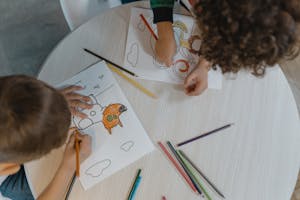 Overhead shot of children coloring, showcasing creativity and education.